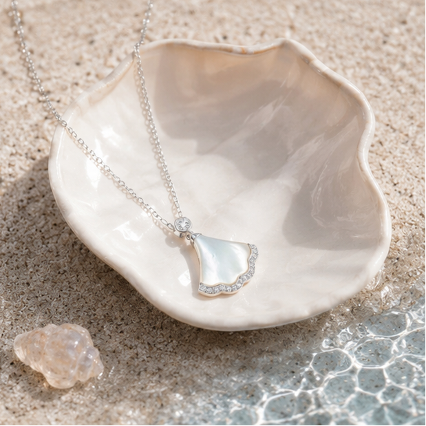 Luxury 925 silver mother of pearl pendant necklace displayed inside a seashell with a soft beach-inspired background.