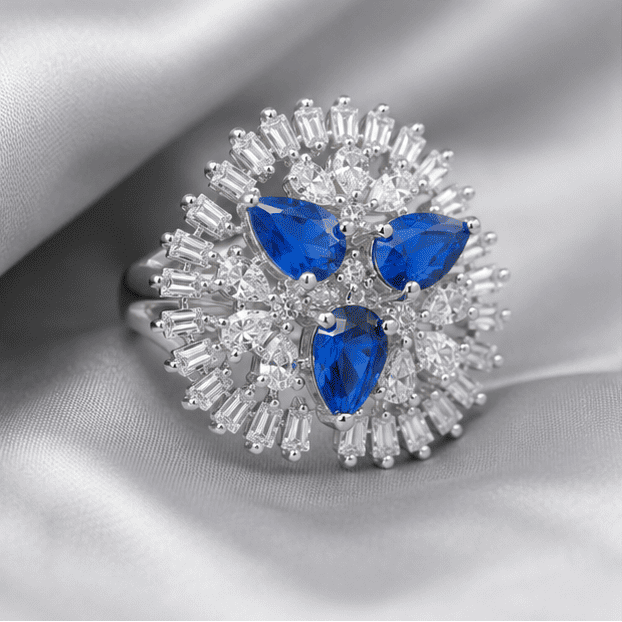 Luxury 925 sterling silver blue floral adjustable ring styled on a grey and silver marble surface with elegant lighting.