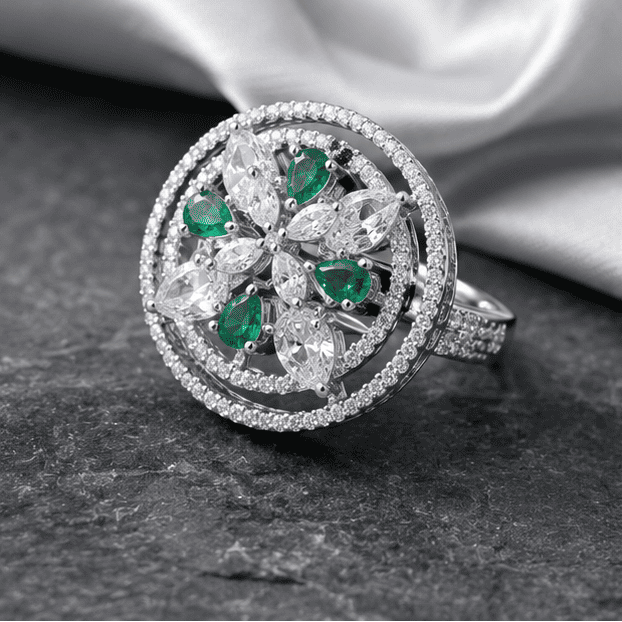 Luxury Emerald Halo Bloom sterling silver statement ring displayed on a grey marble surface with elegant black and silver styling.