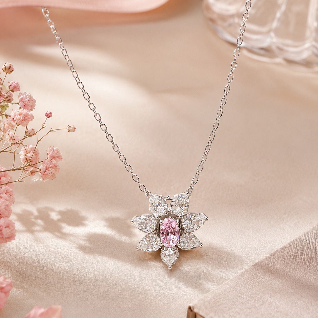 Silver necklace with a pink gemstone pendant on a soft pink background